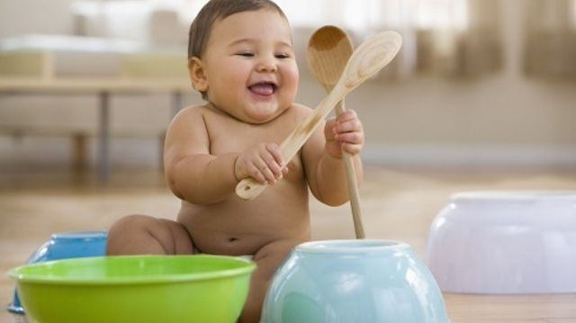 Baby playing with kitchen spoons and bowls